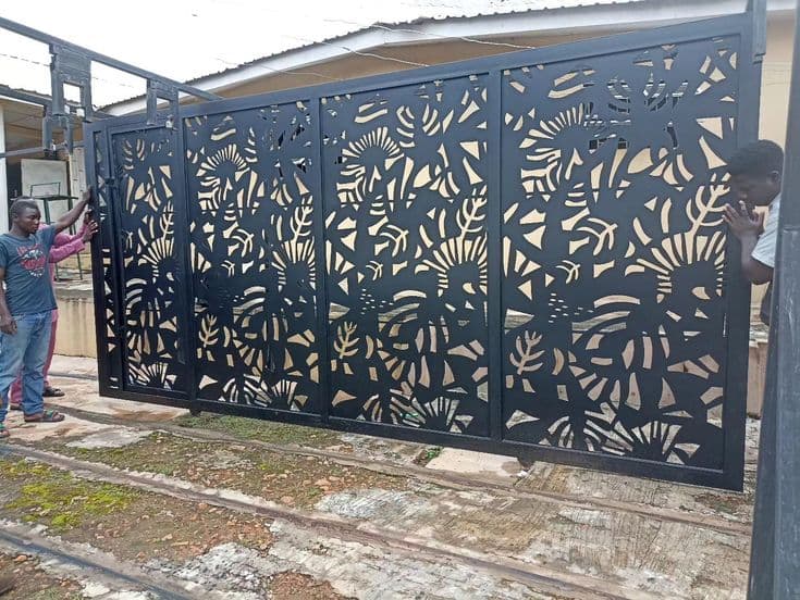 Green shade-net car port with laser-cut decorative steel frame panels spanning two bays